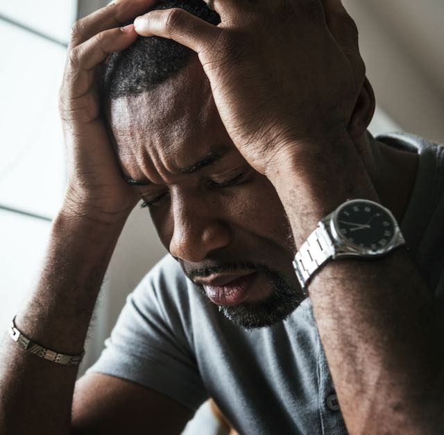 Black man stressing with hands on head