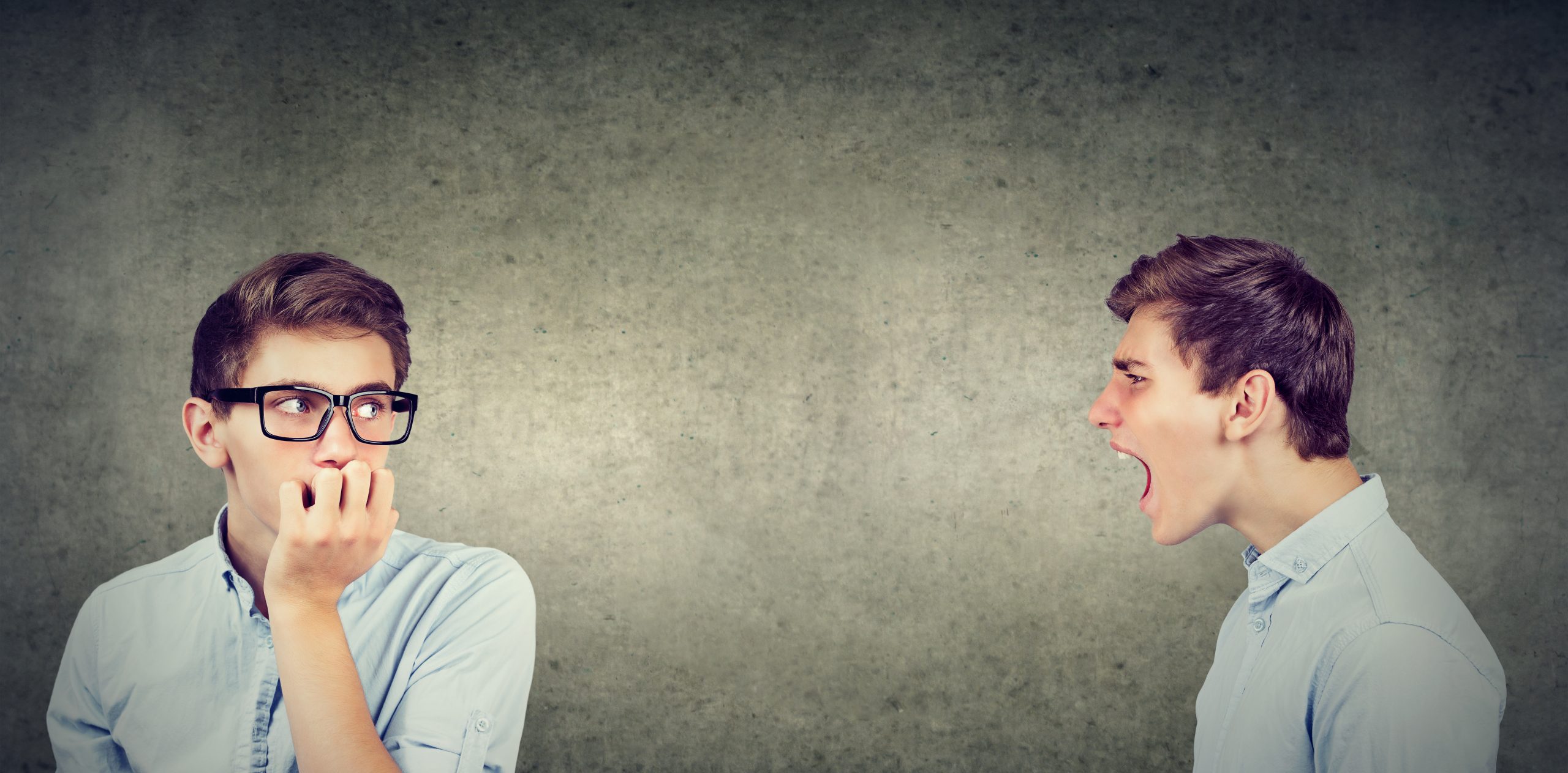 Anxious man in glasses listening to angry, critical version of himself scream at him.