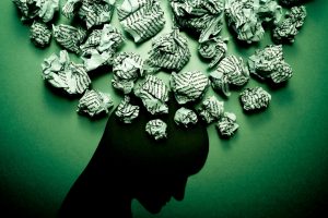 Black silhouette of a head surrounded by crumpled paper balls illustrating repetitive, unresolved thought patterns in persistent depression.