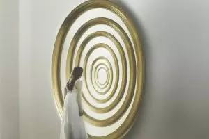 Woman standing in front of concentric circular shapes resembling a tunnel or repeating loop, symbolizing overthinking, mental patterns, and repetitive thought cycles.
