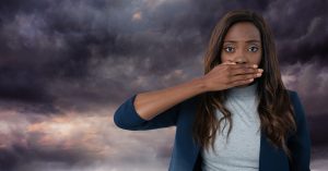 Woman covering her mouth against a dark stormy sky, symbolizing conflict avoidance, self-silencing, and the nervous system response to difficult conversations.