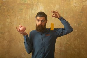 Man holding a piggy bank and a price tag while comparing at-home ketamine therapy costs and treatment value.