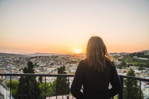 Person overlooking a city at sunset from a scenic viewpoint, symbolizing perspective, possibility, and the broader life changes that can emerge over time.
