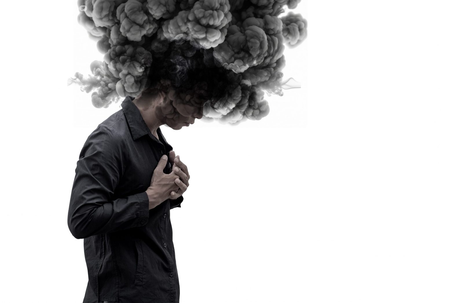 A person stands with their head bowed while a large cloud of dark smoke rises from their head, representing overthinking, emotional overwhelm, and intrusive negative beliefs.
