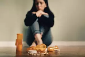 Person sitting on the floor with antidepressant pill bottles in the foreground, representing ongoing depression despite antidepressant treatment.