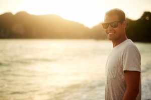 Person standing by a calm lake at sunset, representing the greater sense of calm, emotional ease, and presence that can develop over time with ketamine treatment for anxiety.