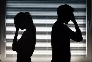 Silhouettes of a man and woman standing back-to-back with their heads bowed, representing the repeating relationship patterns and emotional disconnection explored in the article.