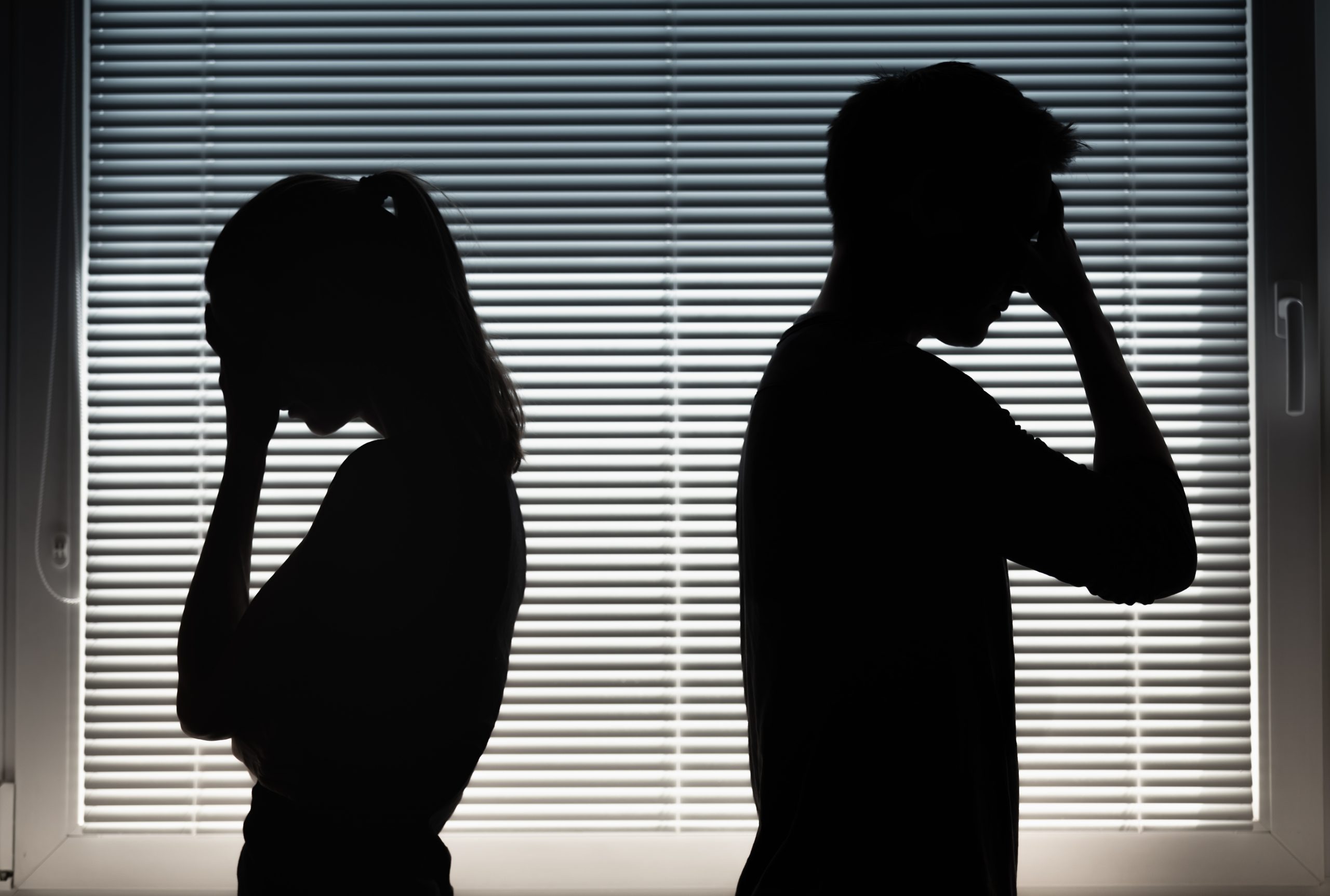 Silhouettes of a man and woman standing back-to-back with their heads bowed, representing the repeating relationship patterns and emotional disconnection explored in the article.