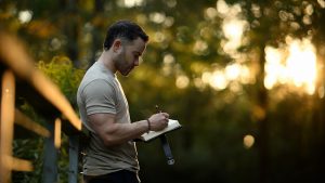 Founder journaling outdoors at sunset, reflecting on old patterns and the daily practice of strengthening his relationship with himself.