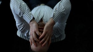 Man leaning back with hands over his face, dealing with big challenges and emotional collapse.