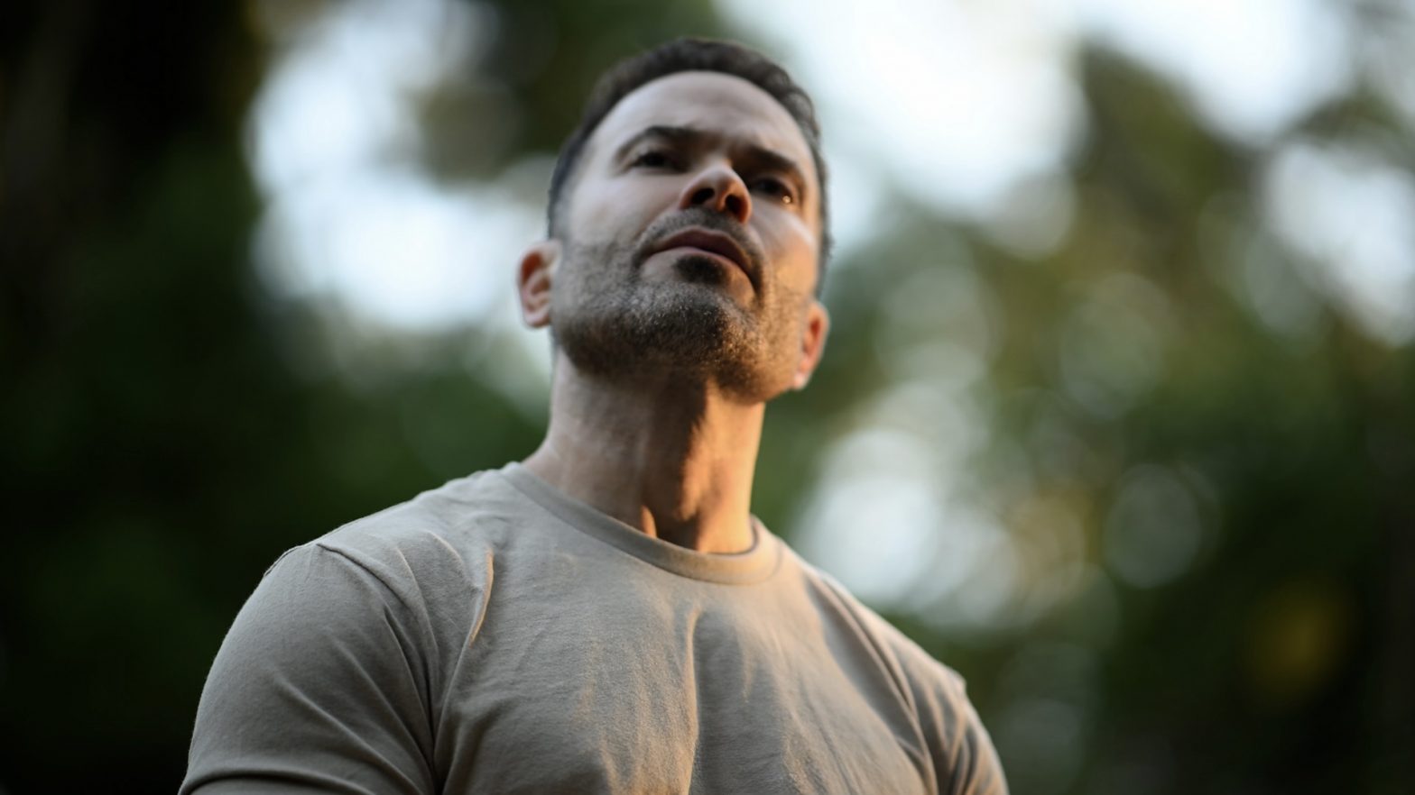 Upwards camera angle on a man looking out thoughtfully, feeling grounded despite external challenges because he has solid inner archetecture.