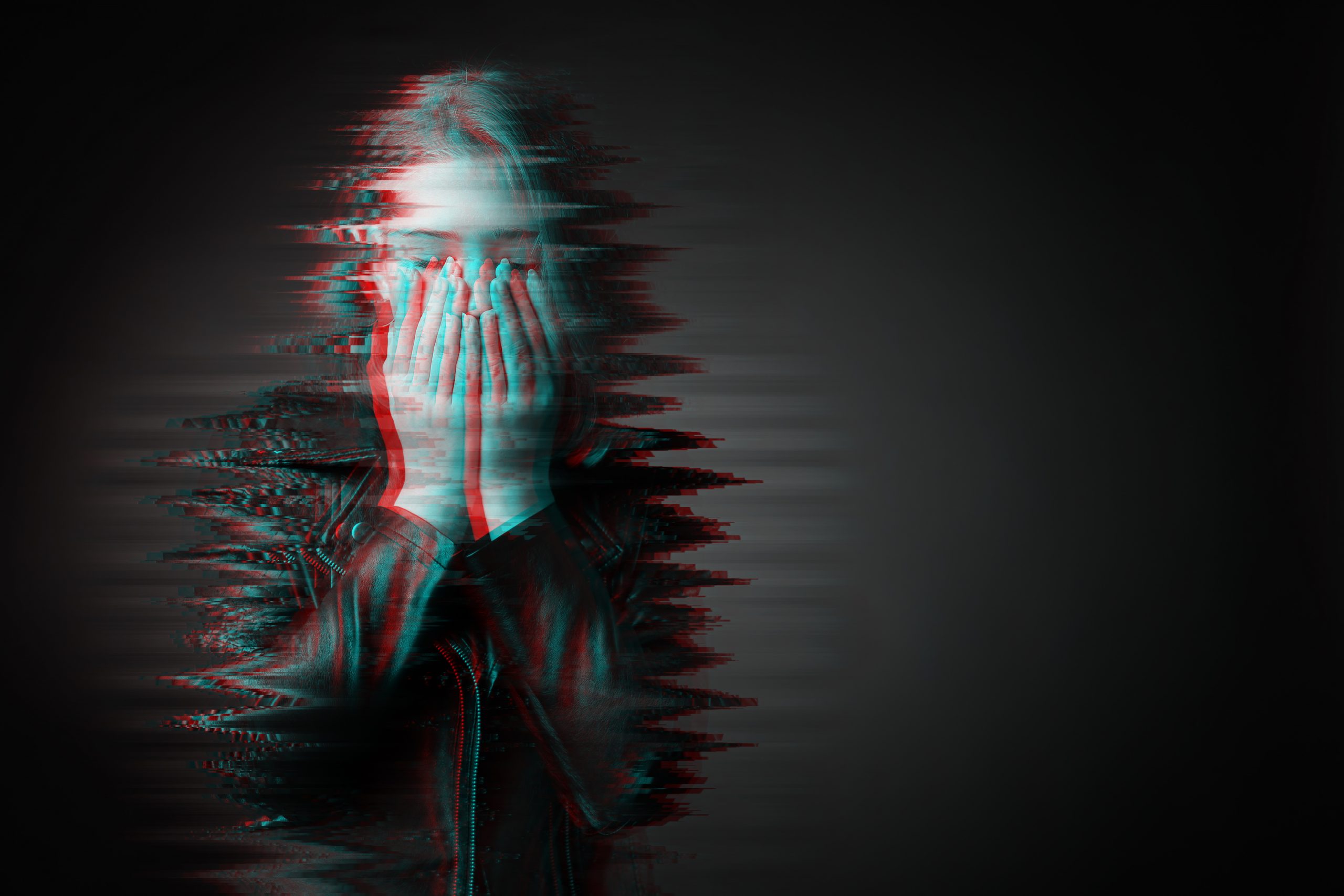 Stylized portrait of woman with hands over her face on black background representing the challenges of trauma healing with talk therapy alone.