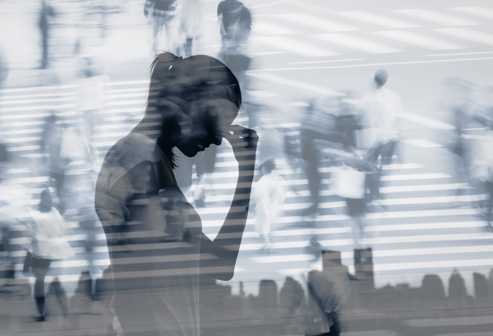 Silhouette of a person holding their head while surrounded by blurred figures, representing stress and emotional exhaustion.