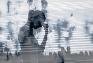 Silhouette of a person holding their head while surrounded by blurred figures, representing stress and emotional exhaustion.