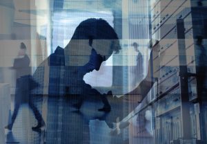 Silhouette of a man with his head bowed, layered over city office buildings and passing commuters, illustrating burnout vs depression and anxiety.